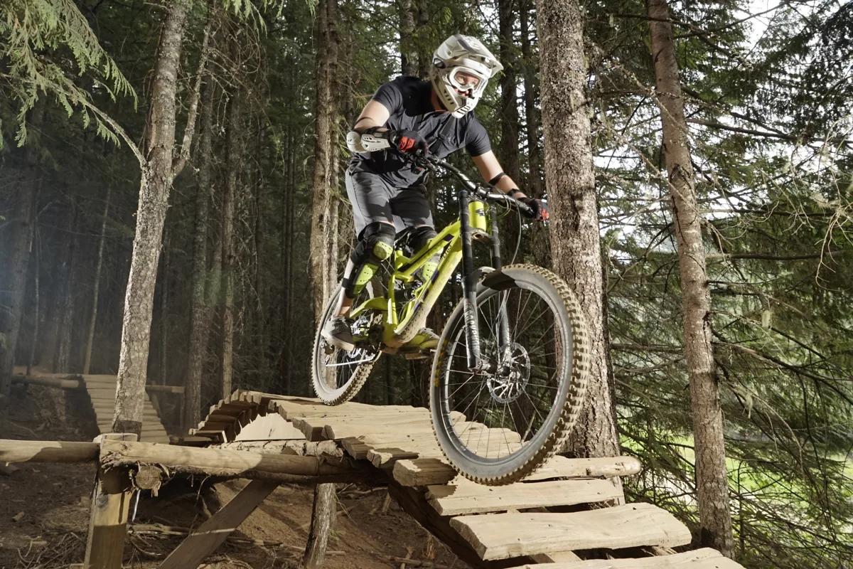 Mark mountain biking over a wooden trail feature in the forest