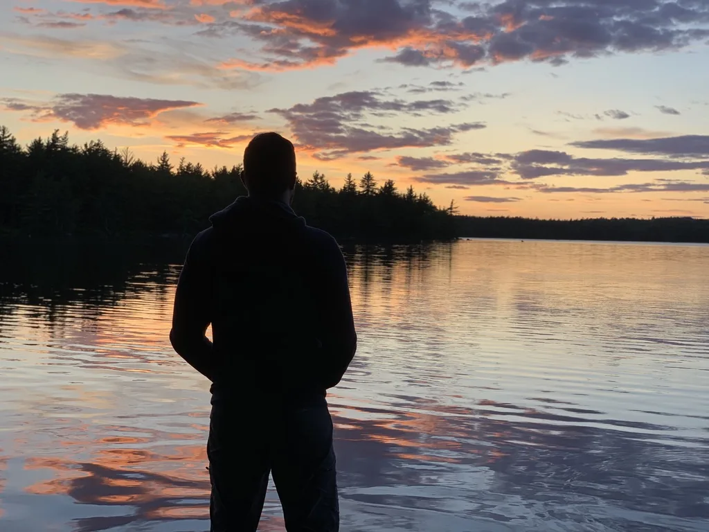 Mark watching a colourful sunset from the edge of the lake